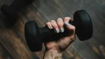 A hand holding a black dumbbell.