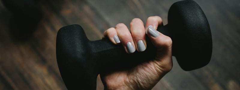 A hand holding a black dumbbell.