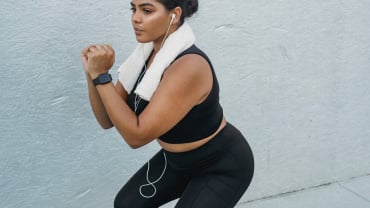 A woman in black exercise gear doing a squat.