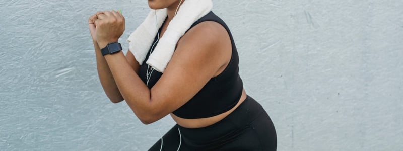 A woman in black exercise gear doing a squat.