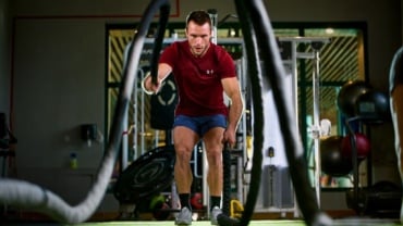 Man using battle ropes in the gym.