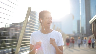 Man looking happy as he jogs on a street with headphones