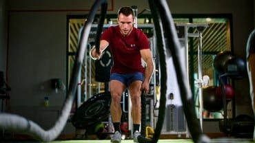 Man using battle ropes in a gym