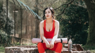 Woman sitting with a rolled up yoga mat