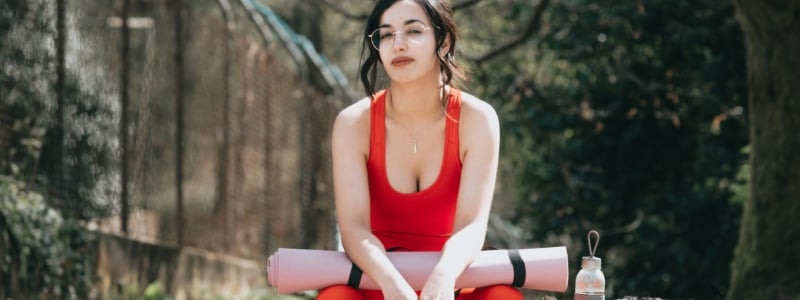 Woman sitting with a rolled up yoga mat