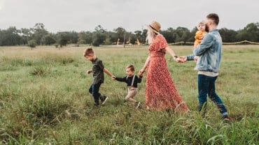 A man, woman and three kids walking in a field