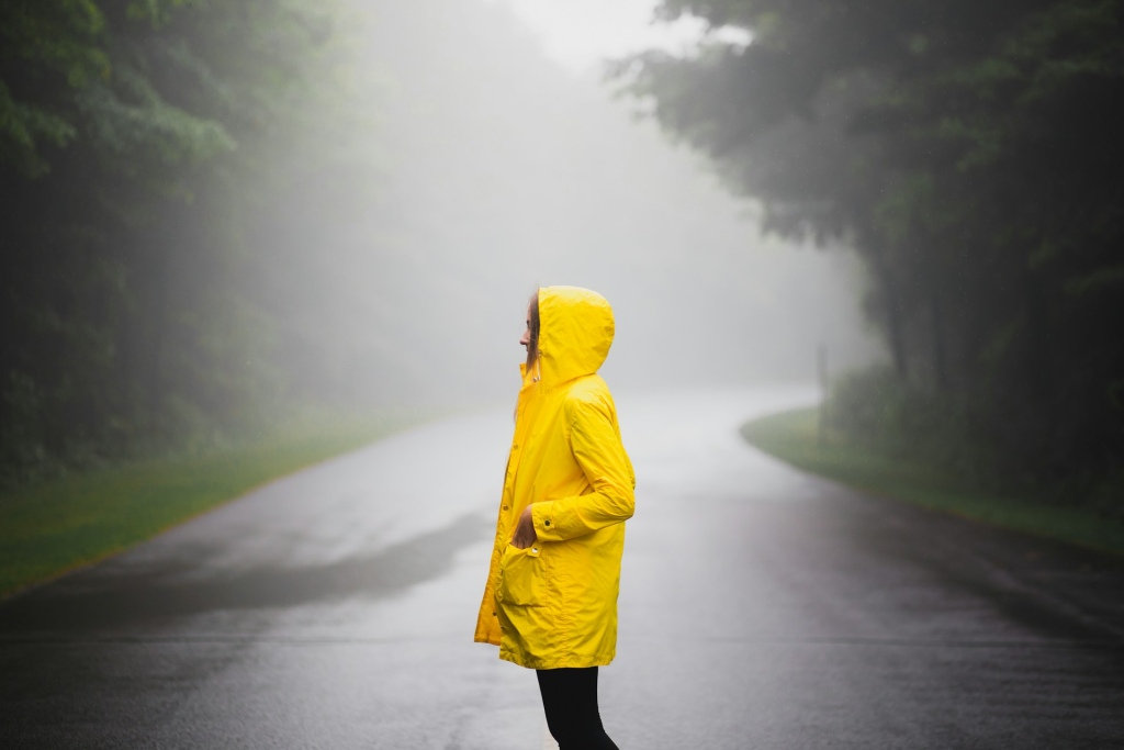 Woman in a fluorescent yellow raincoat with the hood up.