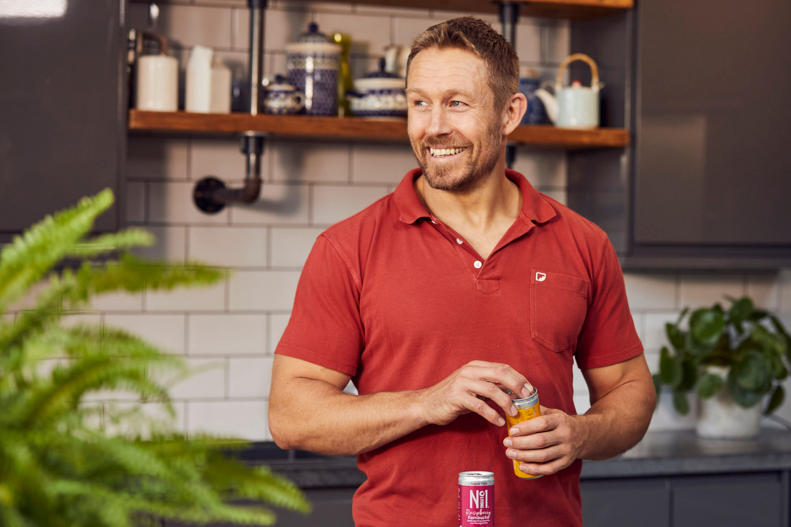 Jonny Wilkinson wearing a red polo shirt opening a bottle