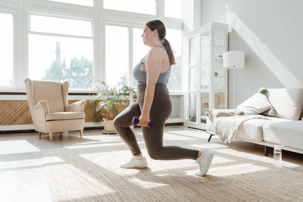 Woman performing a lunge while holding dumbbells.