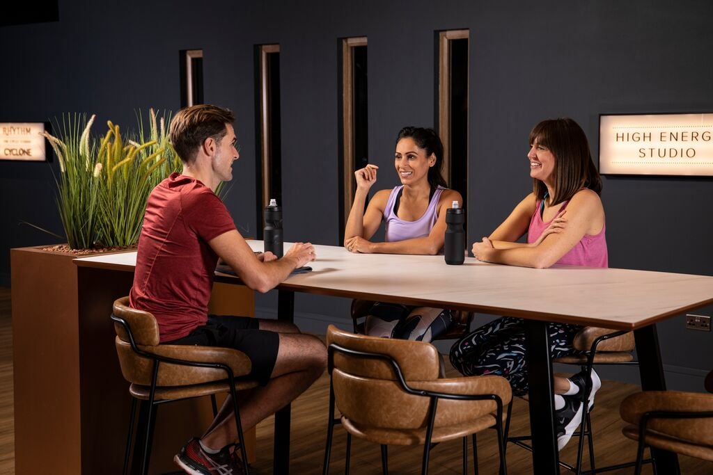 Three people chatting outside an exercise class studio.