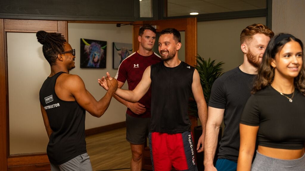 An instructor greeting people as they enter a group exercise studio.