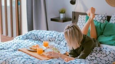 Woman sitting in a shaft of sunlight wearing pyjamas & holding a ceramic mug