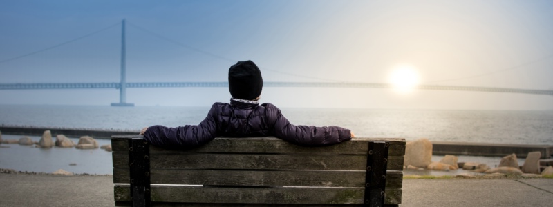 Person sitting on a bench watching the sun rise.