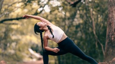 Woman in workout gear stretching in a forest