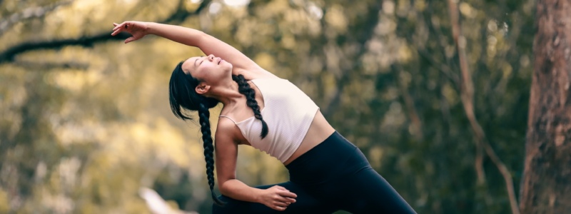 Woman in workout gear stretching in a forest