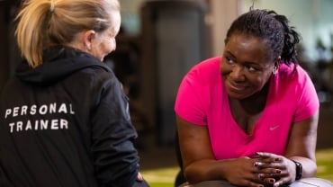 A David Lloyd Clubs personal trainer talking to a female client in the gym.