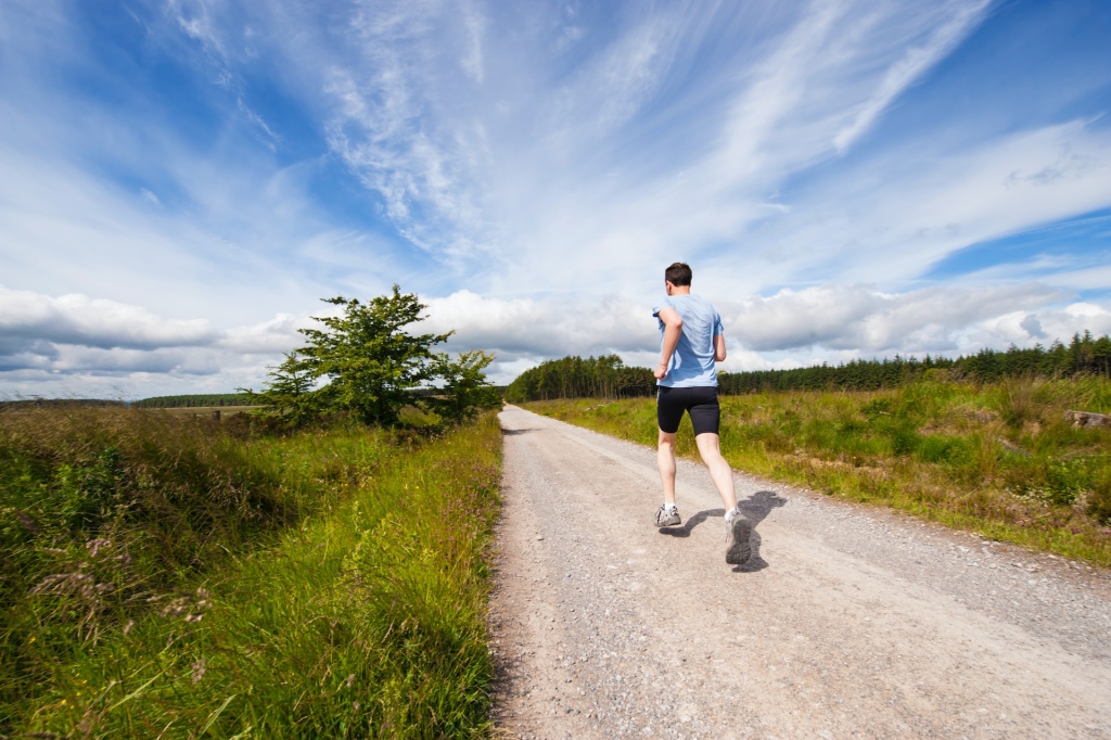 Man photographed from behind running along a quiet country path