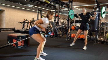 Two women lifting weights in a gym.