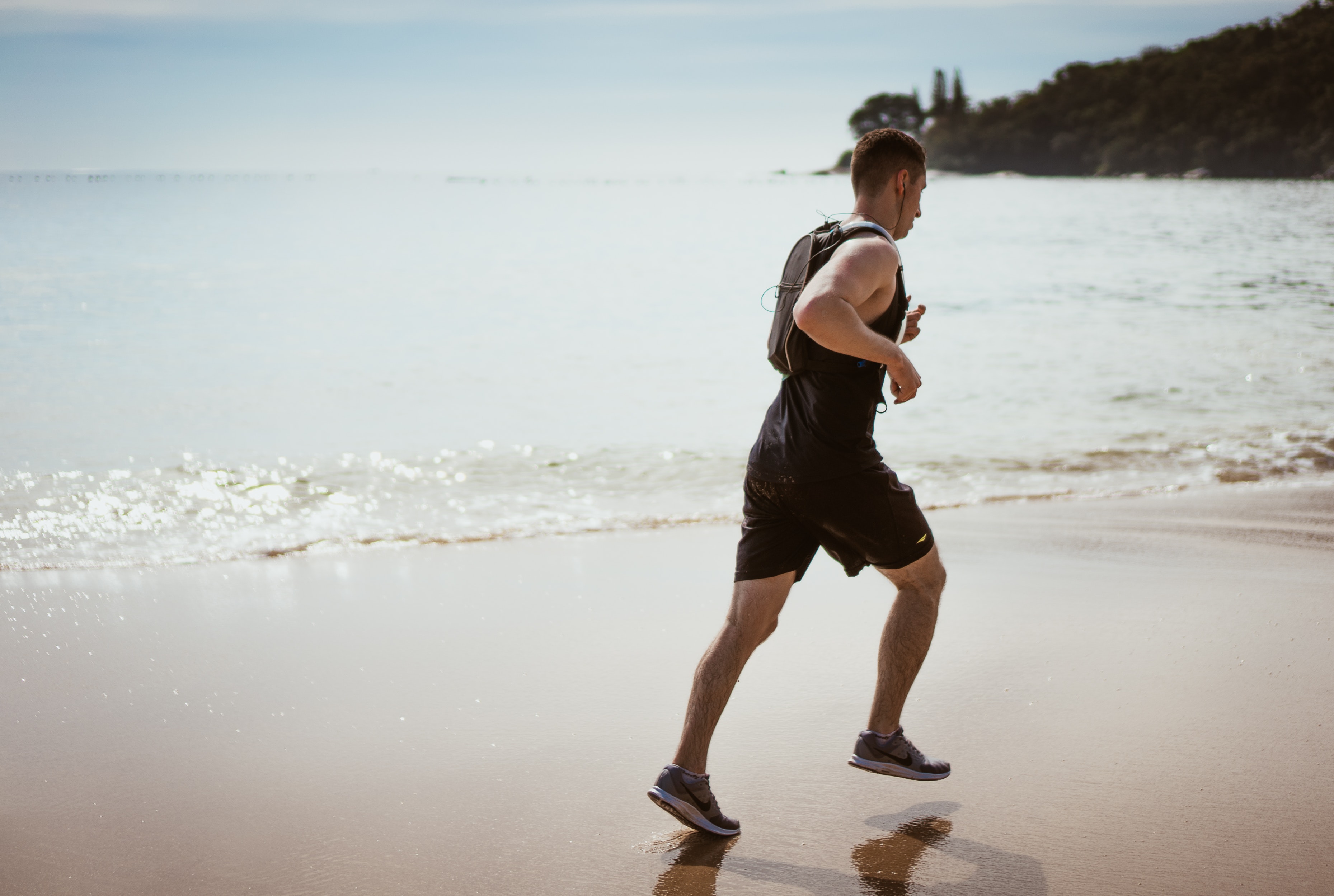 Man running on a white-sand beach on a sunny day