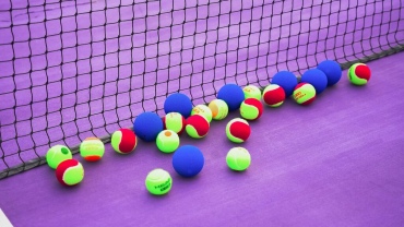 Tennis balls scattered on the floor of a tennis court.