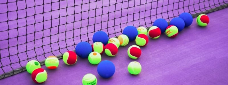 Tennis balls scattered on the floor of a tennis court.