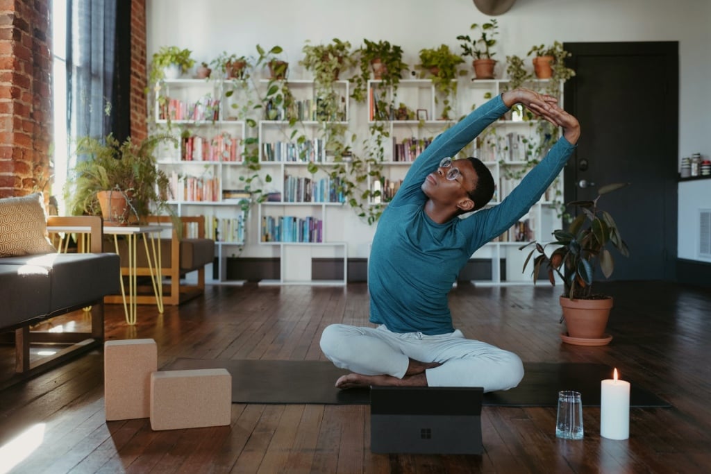 Man doing an overhead arm stretch in a living room