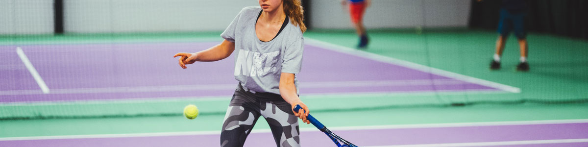 Image of a girl hitting a forehand on a carpet tennis court