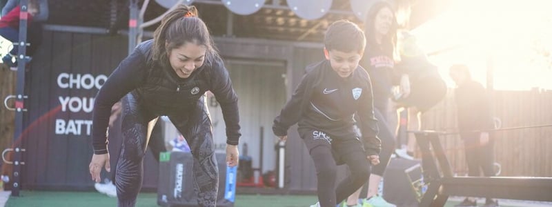 A woman and a boy doing a Battlebox outdoor circuit training session at a David Lloyd Club.