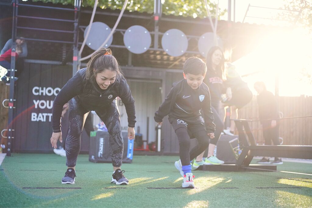 A woman and a boy doing a Battlebox outdoor circuit training session at a David Lloyd Club.