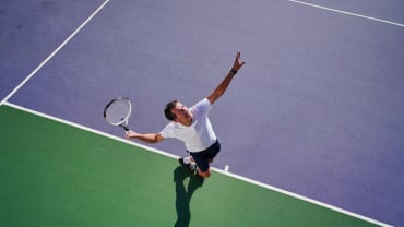 A man serving on an outdoor tennis court.