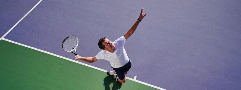 A man serving on an outdoor tennis court.