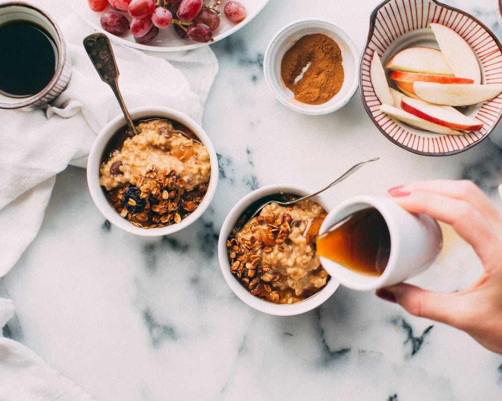 Person pouring syrup onto oatmeal.