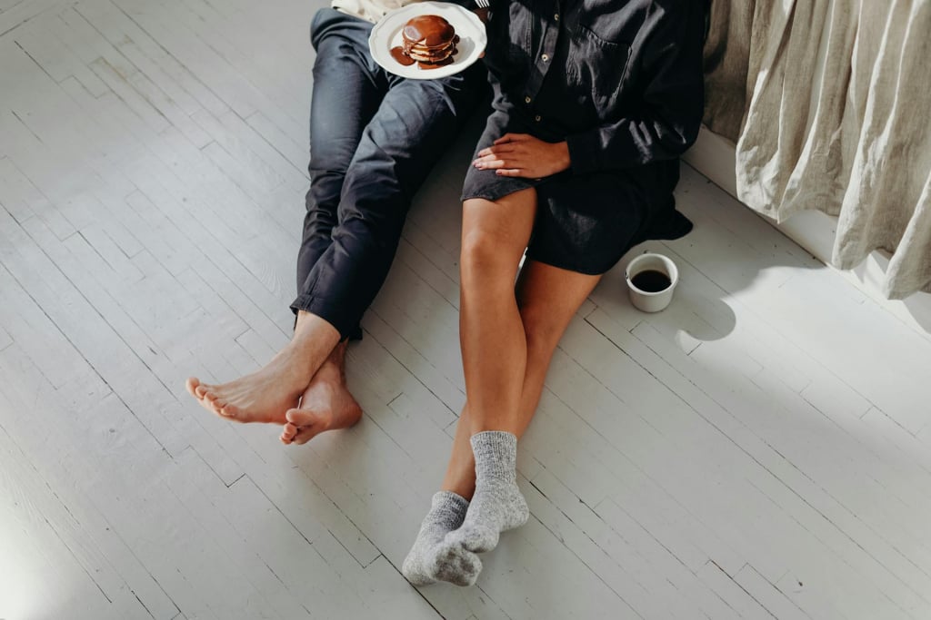 A couple sitting on the floor eating pancakes.