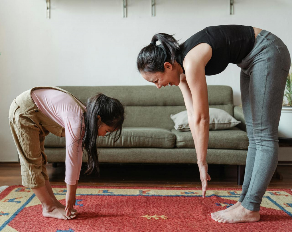 A woman and a girl bending over to touch their toes.