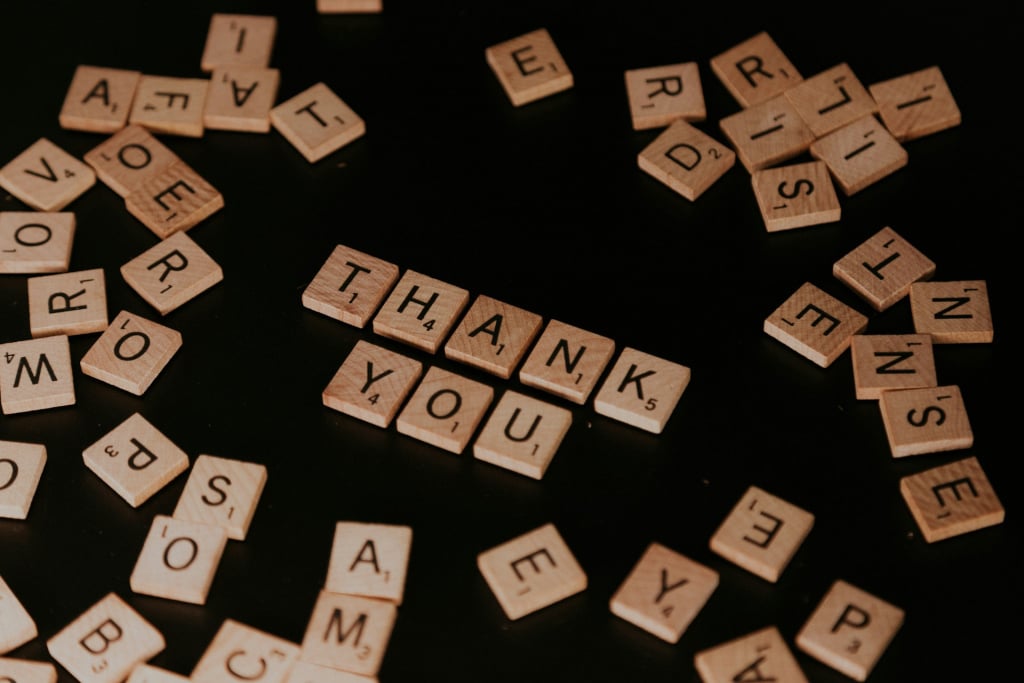 Scrabble tiles spelling out 'thank you'.