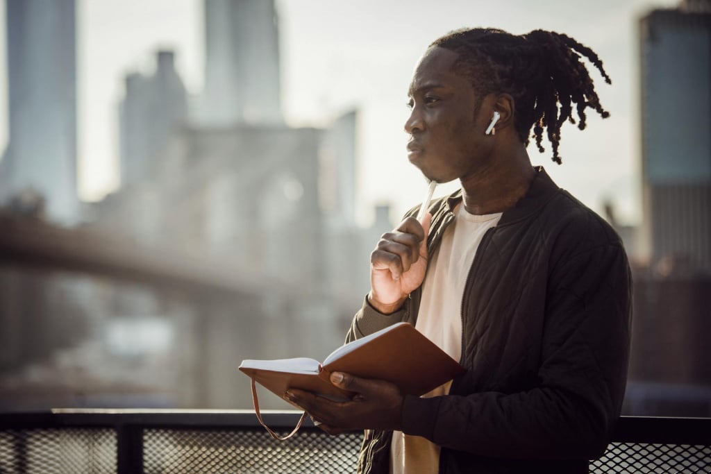 A man holding a notebook and pen, looking thoughtful.