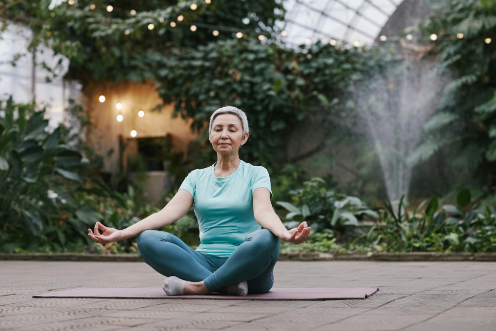 A woman sitting cross-legged with her eyes closed.