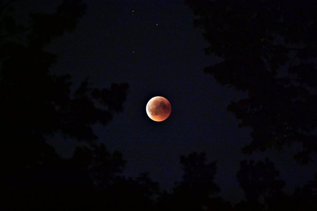 A dark night sky with a full moon and some stars.