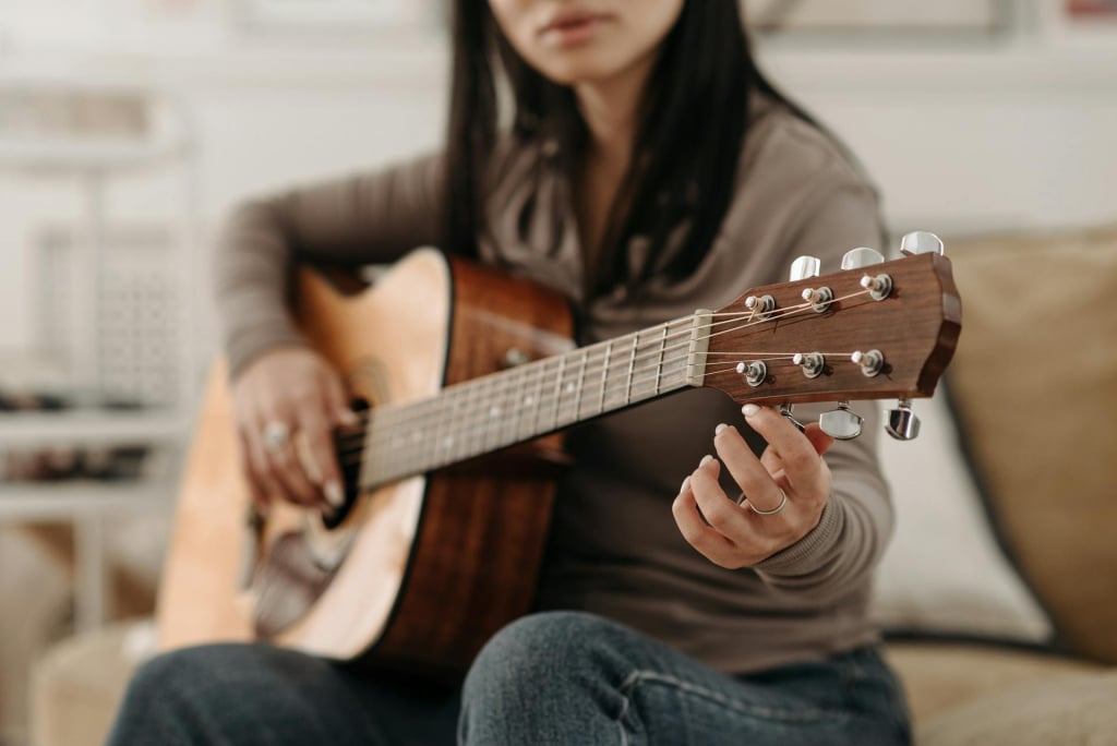 A woman sitting on a sofa holding a guitar.