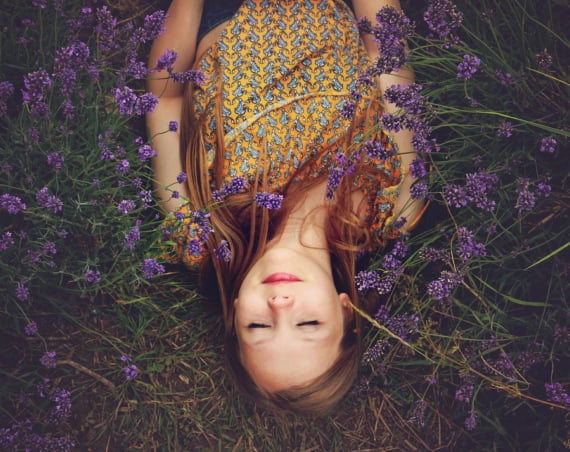 A woman sleeping in a field surrounded by lavender.