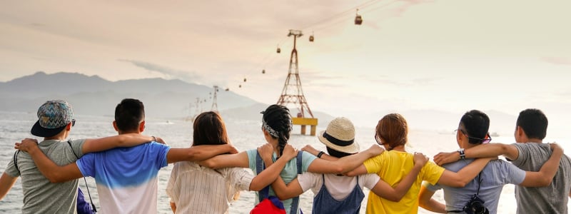 A large group of people. photographed from behind, with their arms around each other.