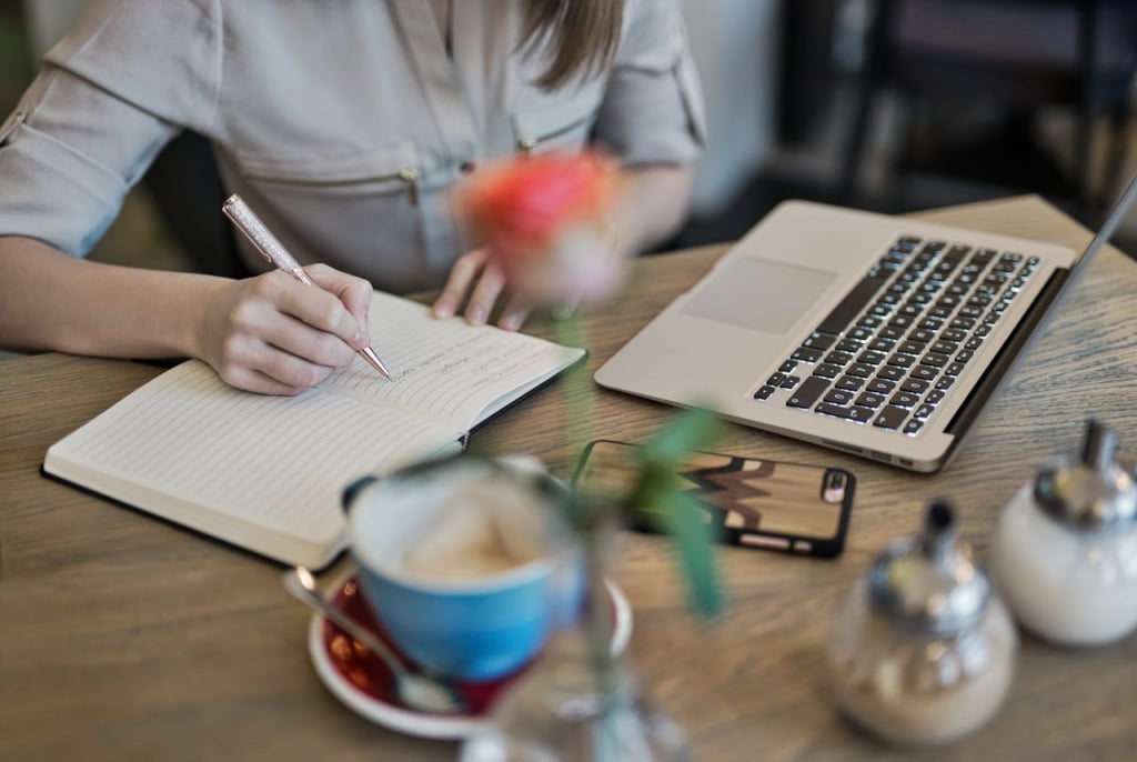 A woman at a desk writing in a notebook.