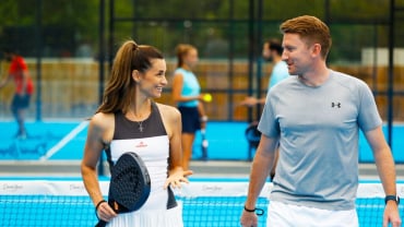 A woman and a man chatting on a Padel court.