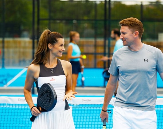 A woman and a man chatting on a Padel court.