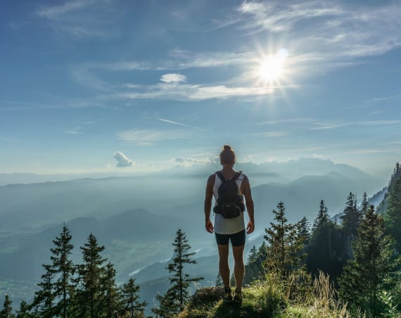 A hiker with a rucksack standing on top of a mountain.