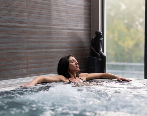 A woman relaxing in an indoor spa pool.