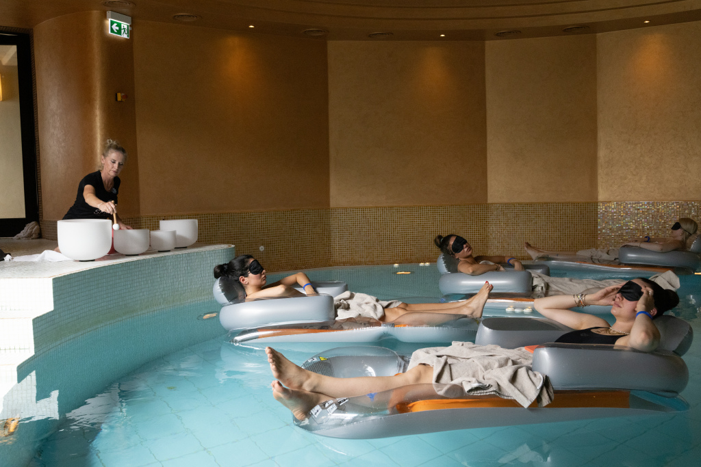 Menschen treiben auf Schwimmreifen in einem Pool während eines Klangbads.