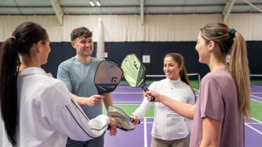 People on a pickleball court holding paddles.