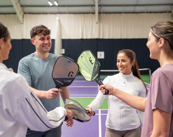 People on a pickleball court holding paddles.