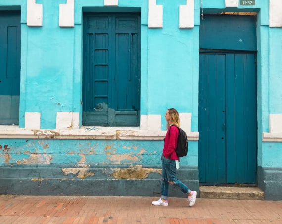A woman walking past a blue building.